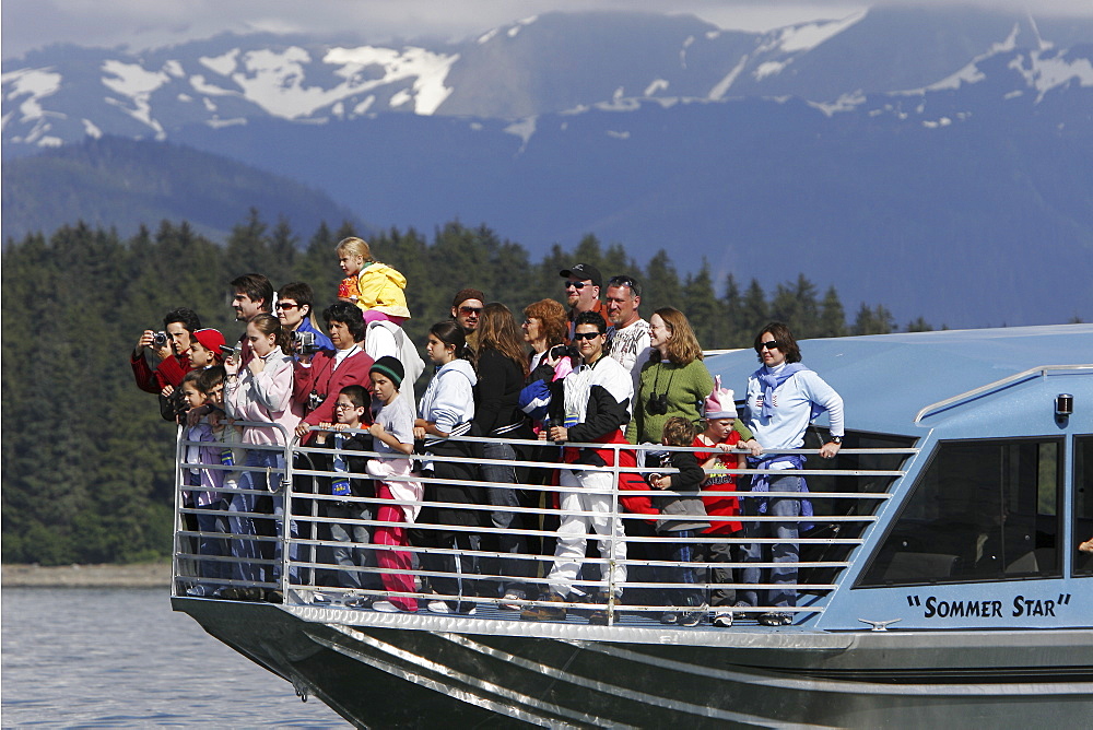 Whale watchers on the bow of a commercial whale watching operation looking for humpback whales in Stephen's Passage just outside Juneau, Southeast Alaska. No model or property releases.