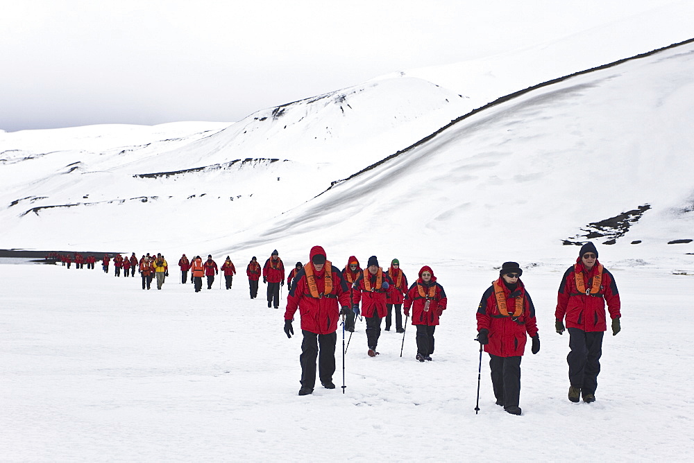 Lindblad Expeditions guests hiking on shorefast ice inside the caldera on Deception Island in Antarctica as part of expedition travel. NO MODEL RELEASES FOR THIS IMAGE.