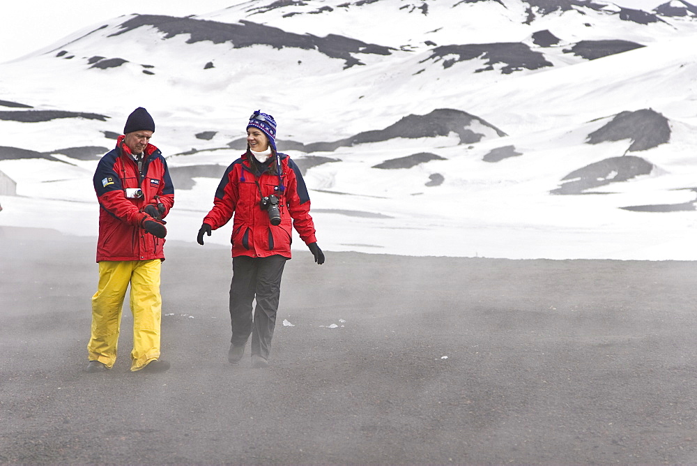 Lindblad Expeditions guests walking the volcanic beach inside the still active caldera on Deception Island in Antarctica as part of expedition travel. NO MODEL RELEASES FOR THIS IMAGE.