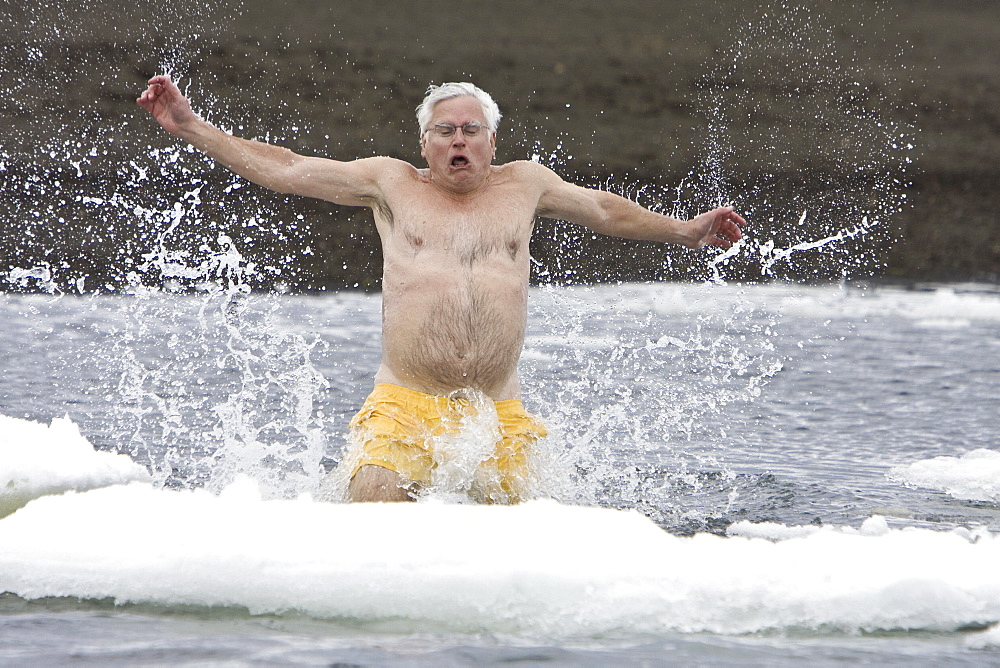 Lindblad Expeditions guest taking the "polar plunge" in Foster Harbor on Deception Island in Antarctica as part of expedition travel. NO MODEL RELEASES FOR THIS IMAGE.