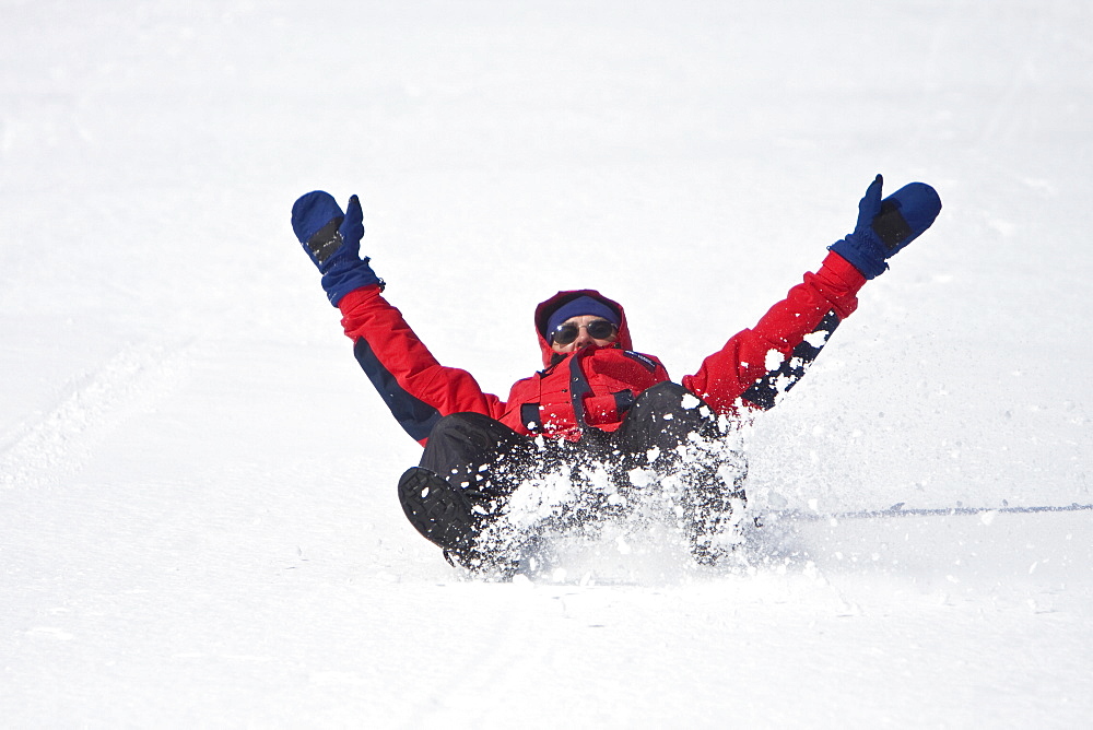 Lindblad Expeditions guests sliding down a hill on their snow pants in Antarctica as part of expedition travel. NO MODEL RELEASES FOR THIS IMAGE.