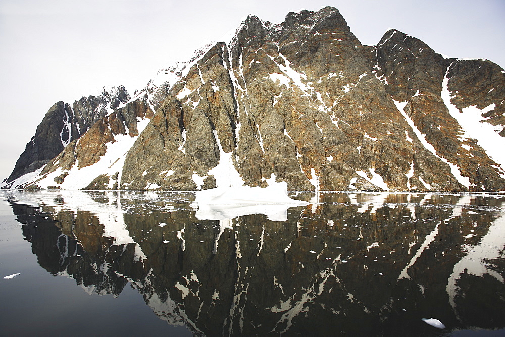 Reflections and snow covered mountains in the Lemaire Channel in Antarctica.