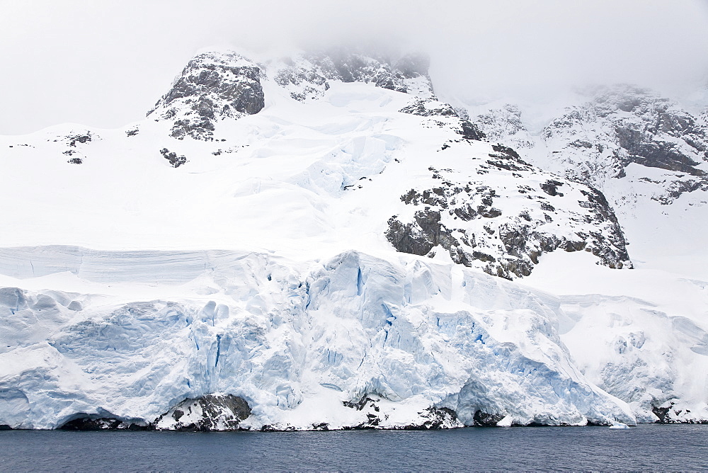 The Lindblad Expedition ship National Geographic Explorer transits Lemaire Channel in late evening light on the west side of the Antarctic peninsula in Antarctica