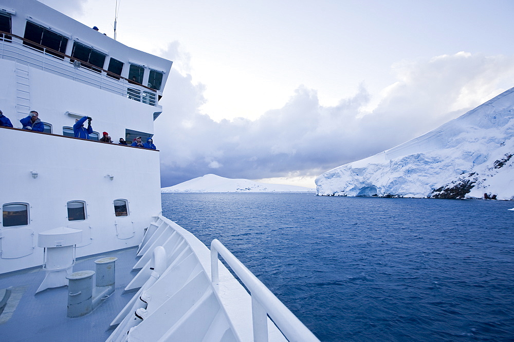 The Lindblad Expedition ship National Geographic Explorer transits Lemaire Channel in late evening light on the west side of the Antarctic peninsula in Antarctica