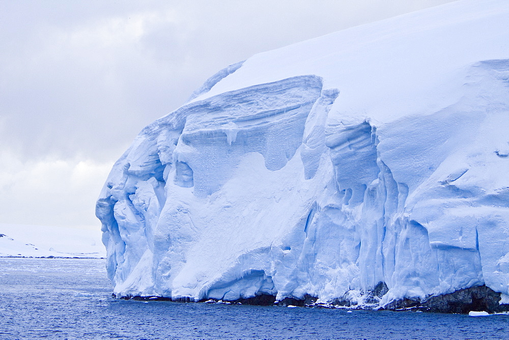 The Lindblad Expedition ship National Geographic Explorer transits Lemaire Channel in late evening light on the west side of the Antarctic peninsula in Antarctica