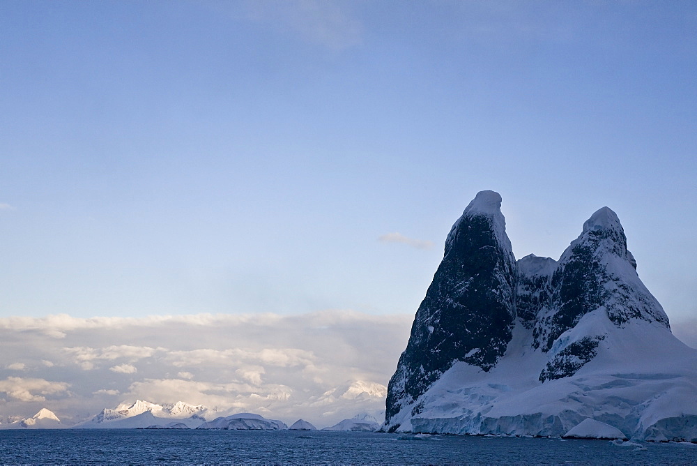 The Lindblad Expedition ship National Geographic Explorer transits Lemaire Channel in late evening light on the west side of the Antarctic peninsula in Antarctica