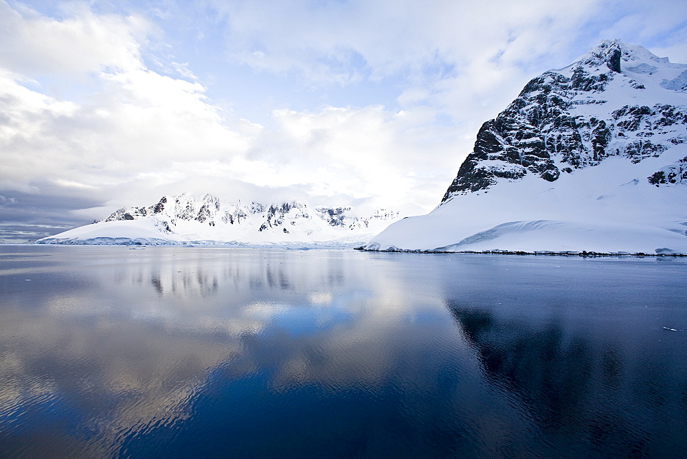 The Lindblad Expedition ship National Geographic Explorer transits Lemaire Channel in late evening light on the west side of the Antarctic peninsula in Antarctica