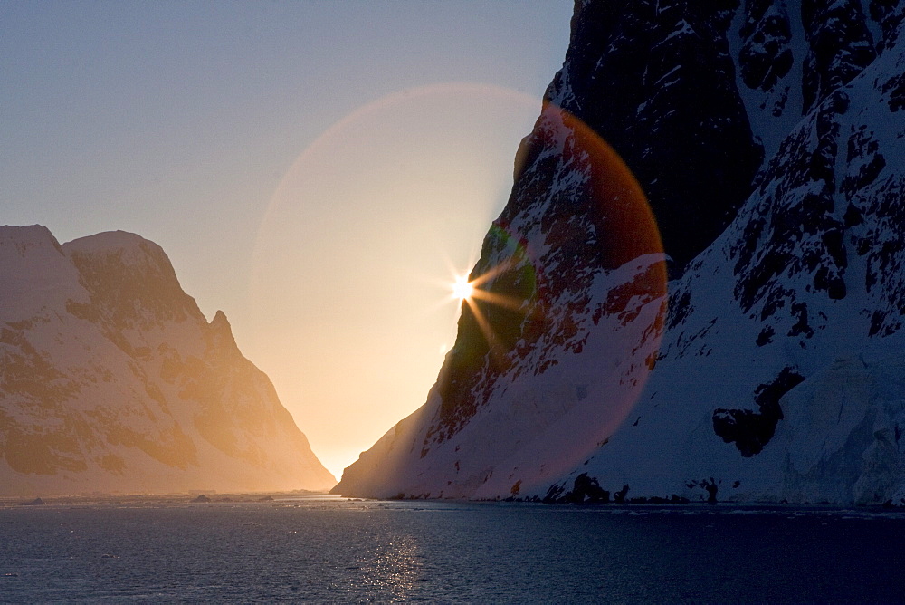 The Lindblad Expedition ship National Geographic Explorer transits Lemaire Channel in late evening light on the west side of the Antarctic peninsula in Antarctica