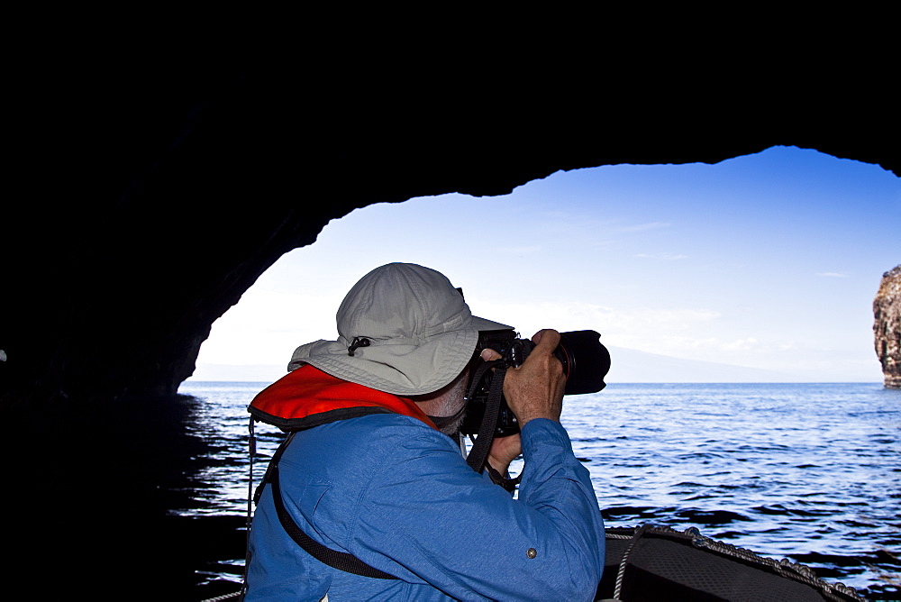 Lindblad Expeditions Guest taking photos inside sea grotto in the Galapagos Island Archipeligo, Ecuador. No model or property release are available for this image.