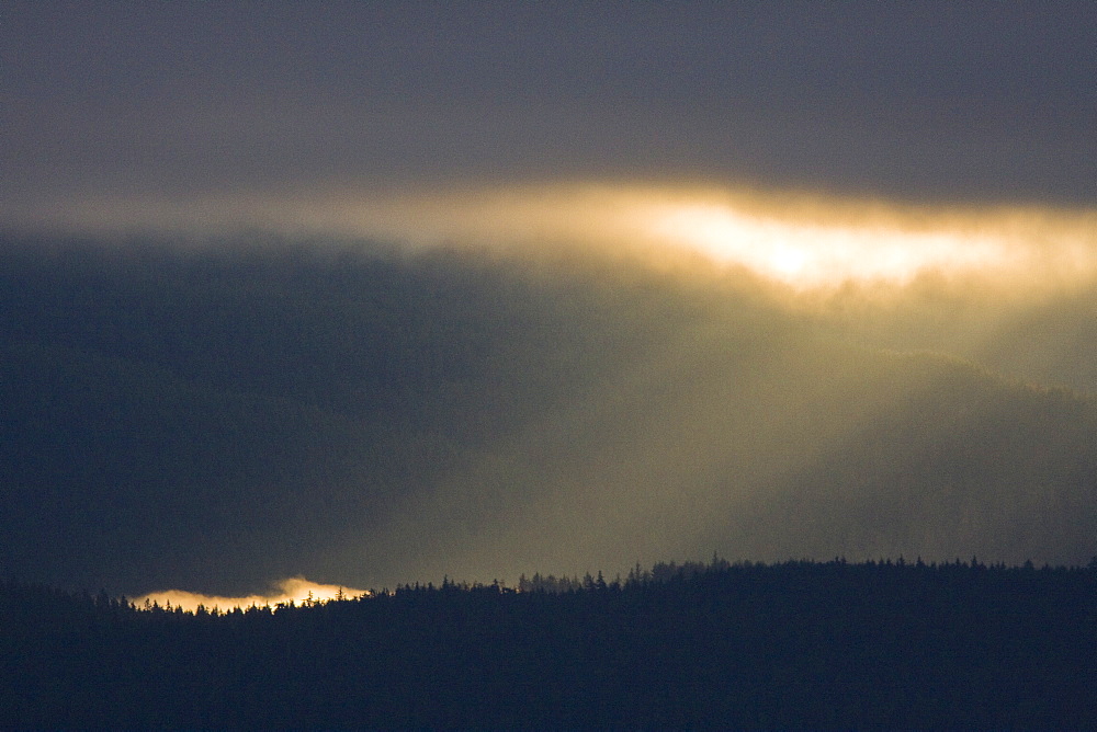 Dramatic early sunrise light over Admiralty Island from Chatham Strait in Southeast Alaska, USA. Pacific Ocean.