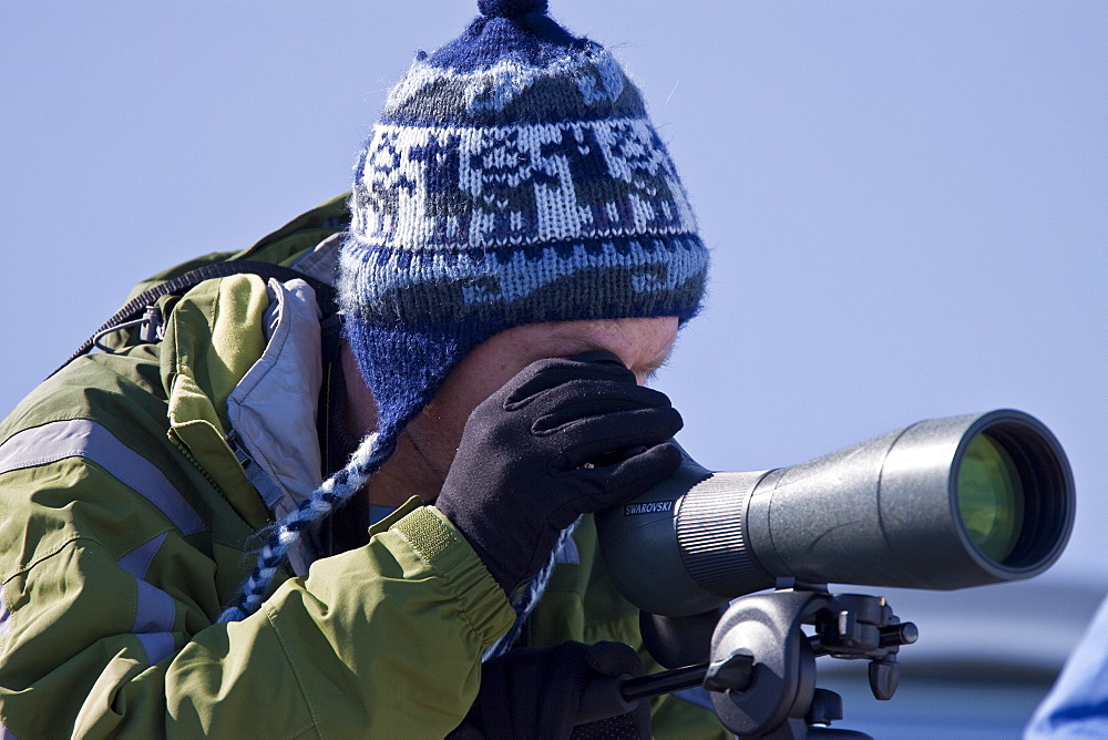 Guest from the Lindblad Expedition ship National Geographic Explorer looks through spotting scope in Antarctica