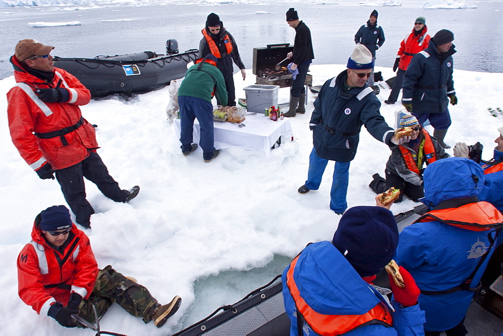 Guests from the Lindblad Expedition ship National Geographic Explorer enjoy a hot asado sandwich prepared by staff at BBQ on an ice floe near Adelaide Island, Antarctica