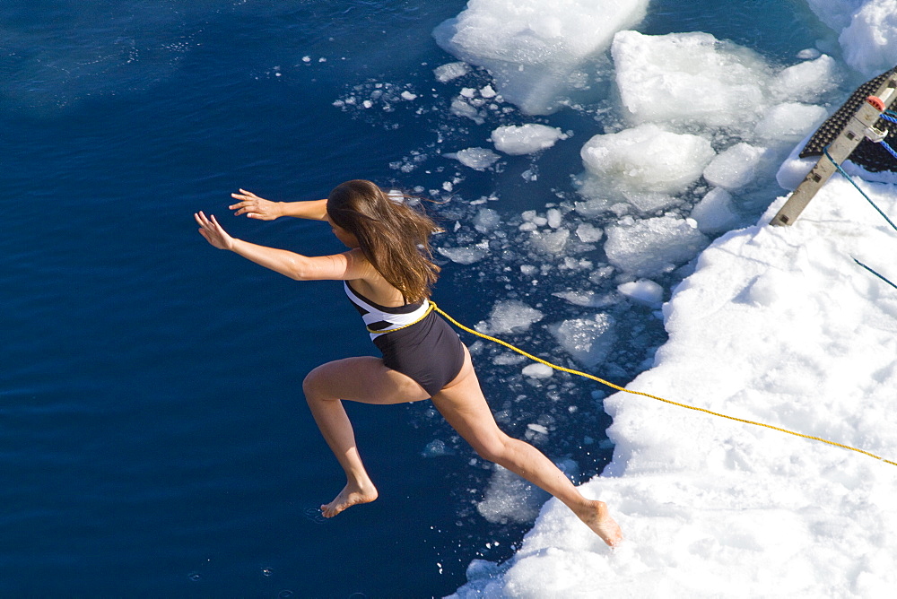 Guests from the Lindblad Expedition ship National Geographic Explorer take the Polar Plunge off ice floe in the Weddell Sea, Antarctica, Southern Ocean