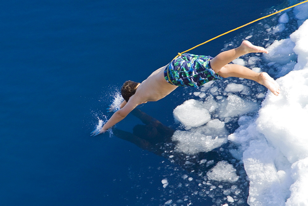 Guests from the Lindblad Expedition ship National Geographic Explorer take the Polar Plunge off ice floe in the Weddell Sea, Antarctica, Southern Ocean