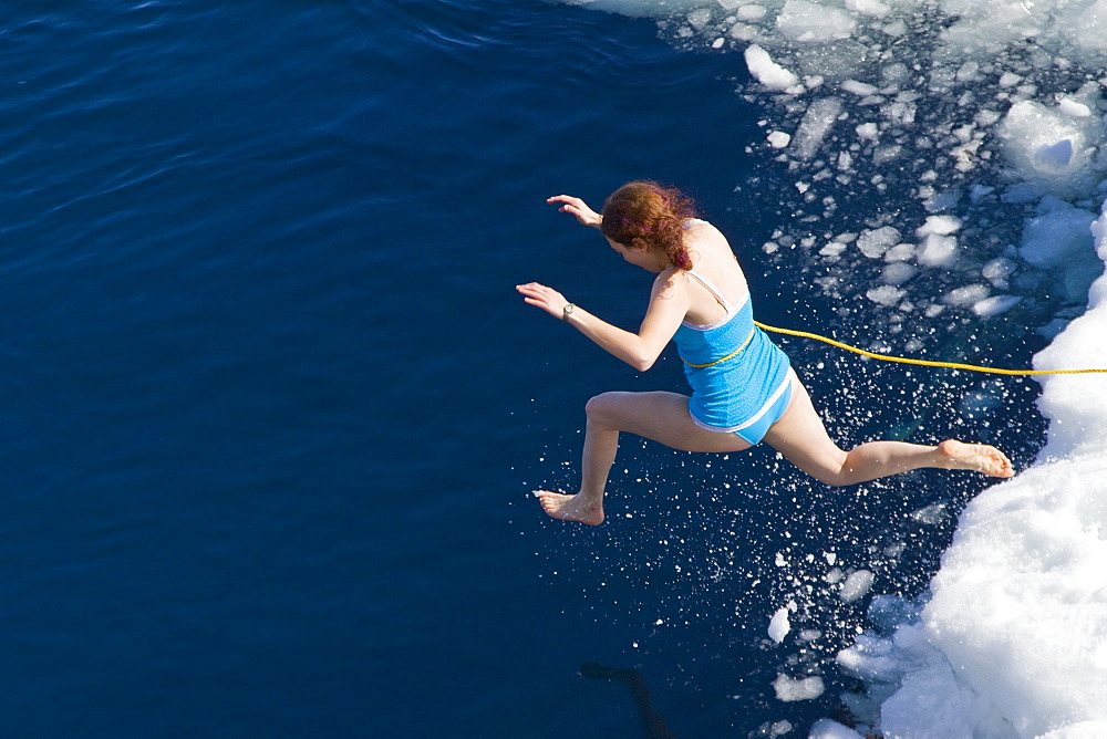 Guests from the Lindblad Expedition ship National Geographic Explorer take the Polar Plunge off ice floe in the Weddell Sea, Antarctica, Southern Ocean