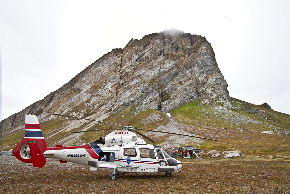 Helicopter bringing supplies to repair the hunters cabin at Gnalodden cliff in Hornsund, Norway