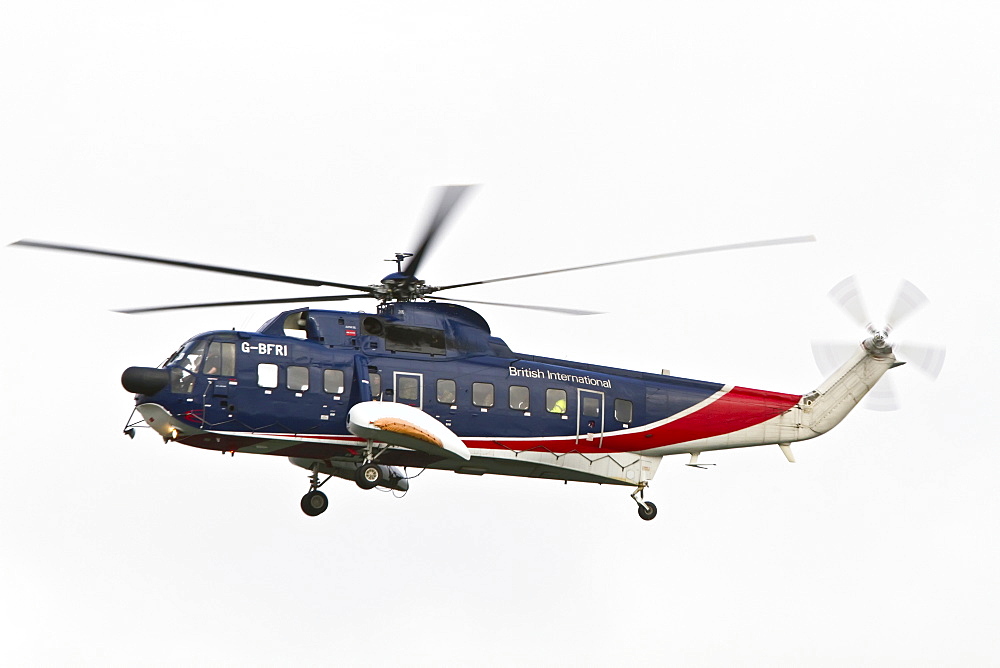 British International helicopter flying over the outer harbor of Stanley on East Island, Falkland Islands, South Atlantic Ocean.