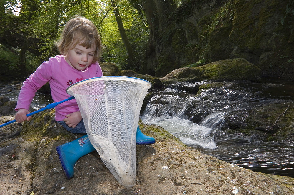 Young girl with net beside a waterfall, Arbirlot, Angus, Scotland