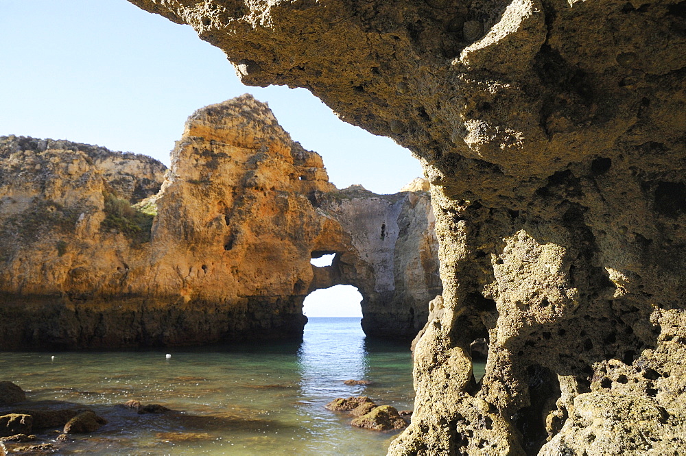 Weathered sandstone rocks and natural archway at Ponta da Piedade at low tide, Lagos, Algarve, Portugal, Europe