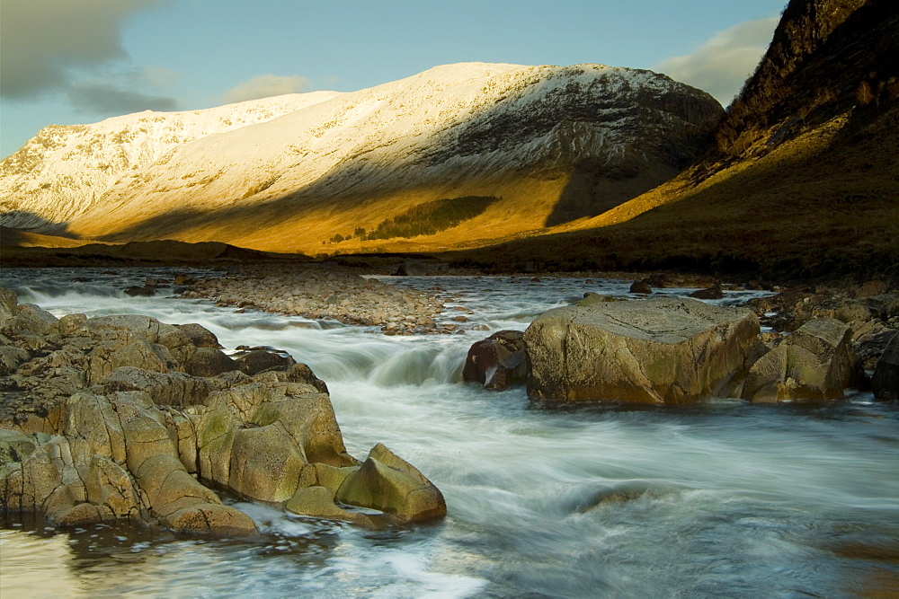 River Etive flowing through Glen Etive in winter with moon on horizon. Slow shutter speed. Argyll Scotland, UK