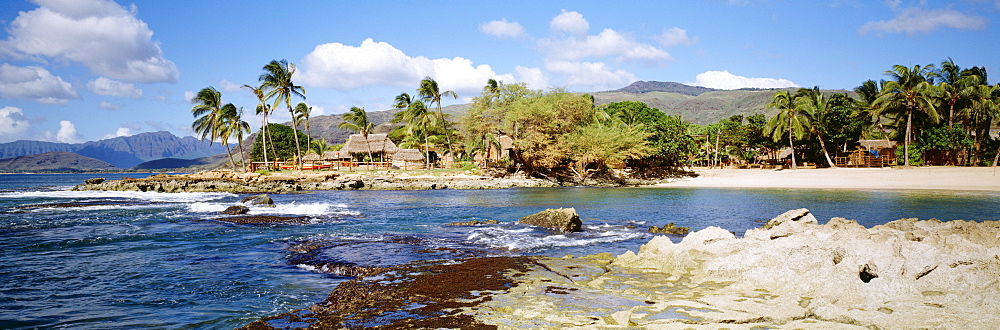 Hawaii, Oahu, Paradise Cove, Thatched huts along shoreline.