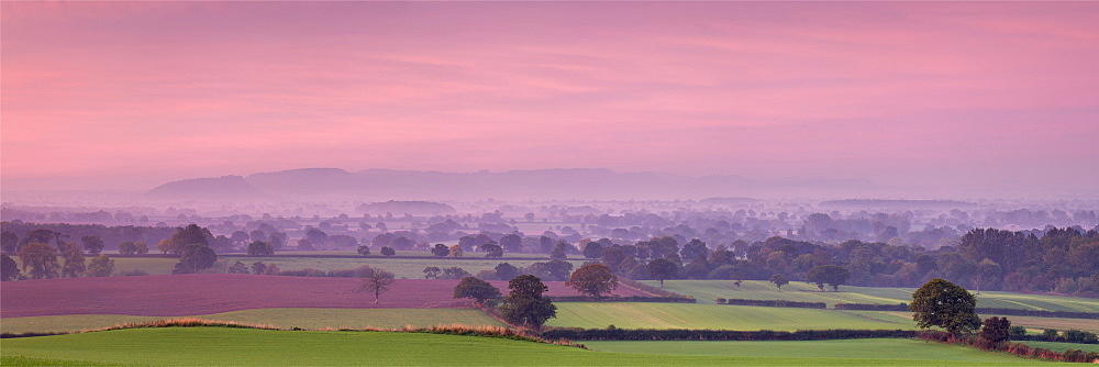 Autumn dawn across the Cheshire plain with Beeston Castle and the Peckforton Hills receding into the morning mist, Cheshire, England, United Kingdom, Europe