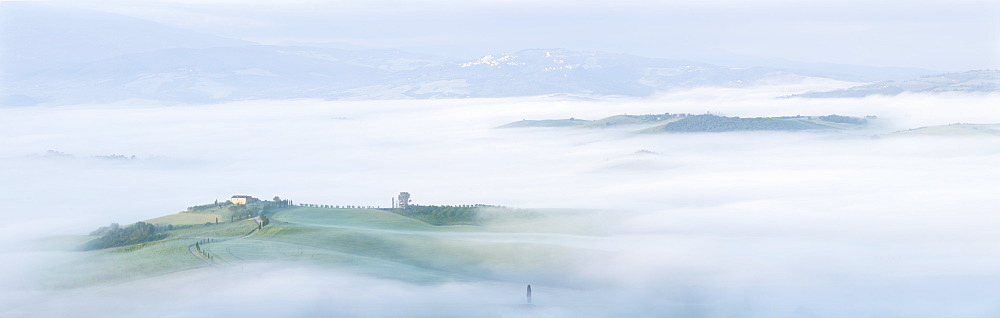 Panoramic view of the Val d'Orcia with fog dispersing to reveal a Tuscan farmhouse perched on a small hill, UNESCO World Heritage Site, Tuscany, Italy, Europe