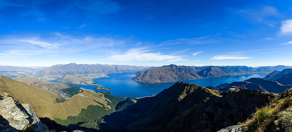 Steep sharp mountains, a deep blue lake, and mountain town in Queenstown, Otago, South Island, New Zealand, Pacific