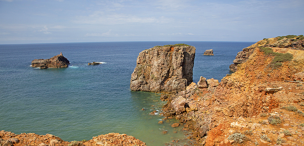 Coastal stacks and stumps, orange coloured crumbling cliffs rise from Atlantic Ocean at Cabo de Sao Vicente (Cape St Vincent), Algarve, Portugal, Europe