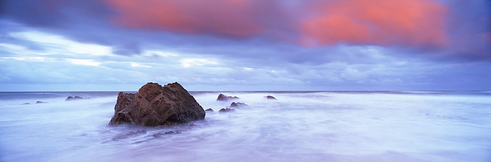 Widemouth Bay at sunrise, with offshore rocks and red storm clouds overhead, near Bude, Cornwall, England, United Kingdom, Europe