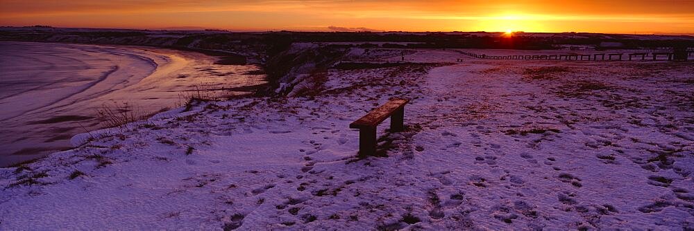 Bench on a snow covered landscape, Filey Bay, Yorkshire, England