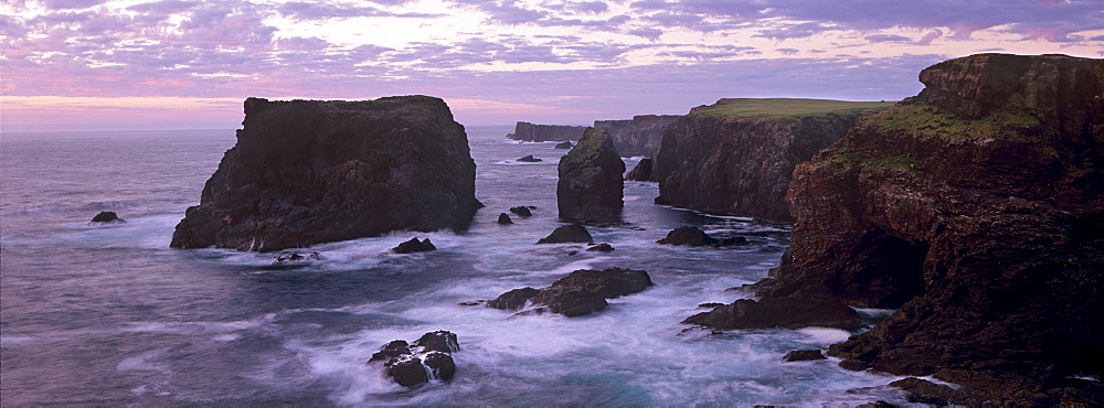 Sunset at Eshaness basalt cliffs, with Moo Stack on left, and deeply eroded coast with caves, blowholes and stacks, Northmavine, Shetland Islands, Scotland, United Kingdom, Europe