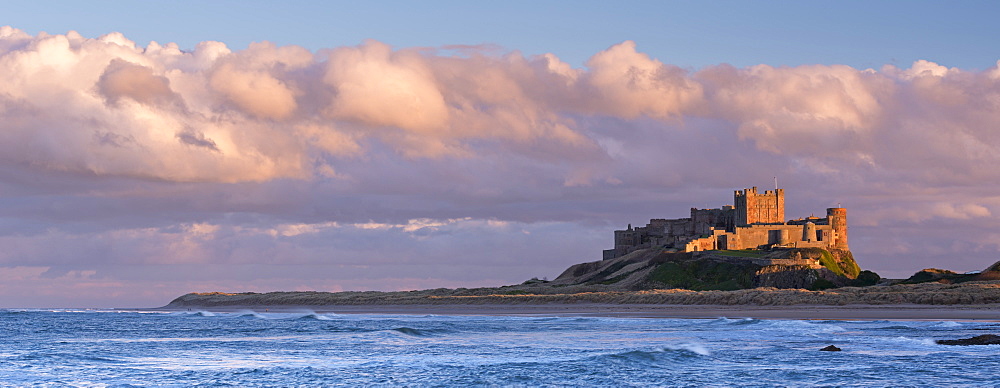 Late evening sunlight bathes the Bamburgh Castle stronghold on the Northumberland coast, Northumberland, England, United Kingdom, Europe