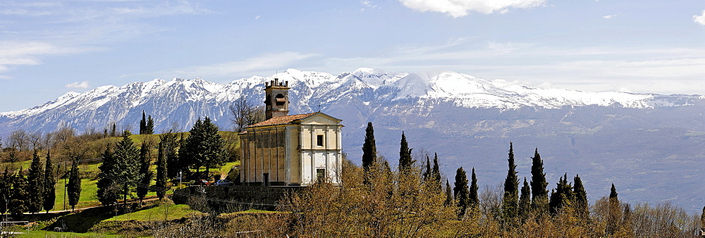 Church and the snow covered Monte Baldo massiv, Sasso, Garda lake, Italy