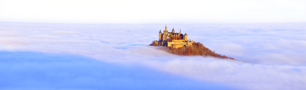 Burg Hohenzollern castle in morning light, mist, with autumn forest, Schwaebische Alb, Swabian Alb, Baden-Wuerttemberg, Germany, Europe