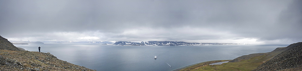 Whalebone Alley grand vista, female tourist standing on cliff face, Itygran Island (Bering Sea) Russia, Asia.  MORE INFO: Whale Bone Alley was discovered by Soviet archaeologists in 1976, but has remained untouched since and little is known of this place. There is a long double line of bowhead whale bones -- jaws and ribs -- running parallel along the shore for hundreds of yards. Many of the bones, especially the enormous jaw bones, are still standing, propped up by lichen-covered rocks. The location is thought to have been used in about 1300 as a ceremonial site, for a men's secret society or feasting site.