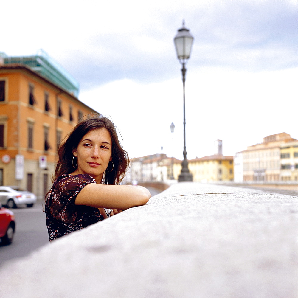 Young woman leaning against wall, Pisa, Italy