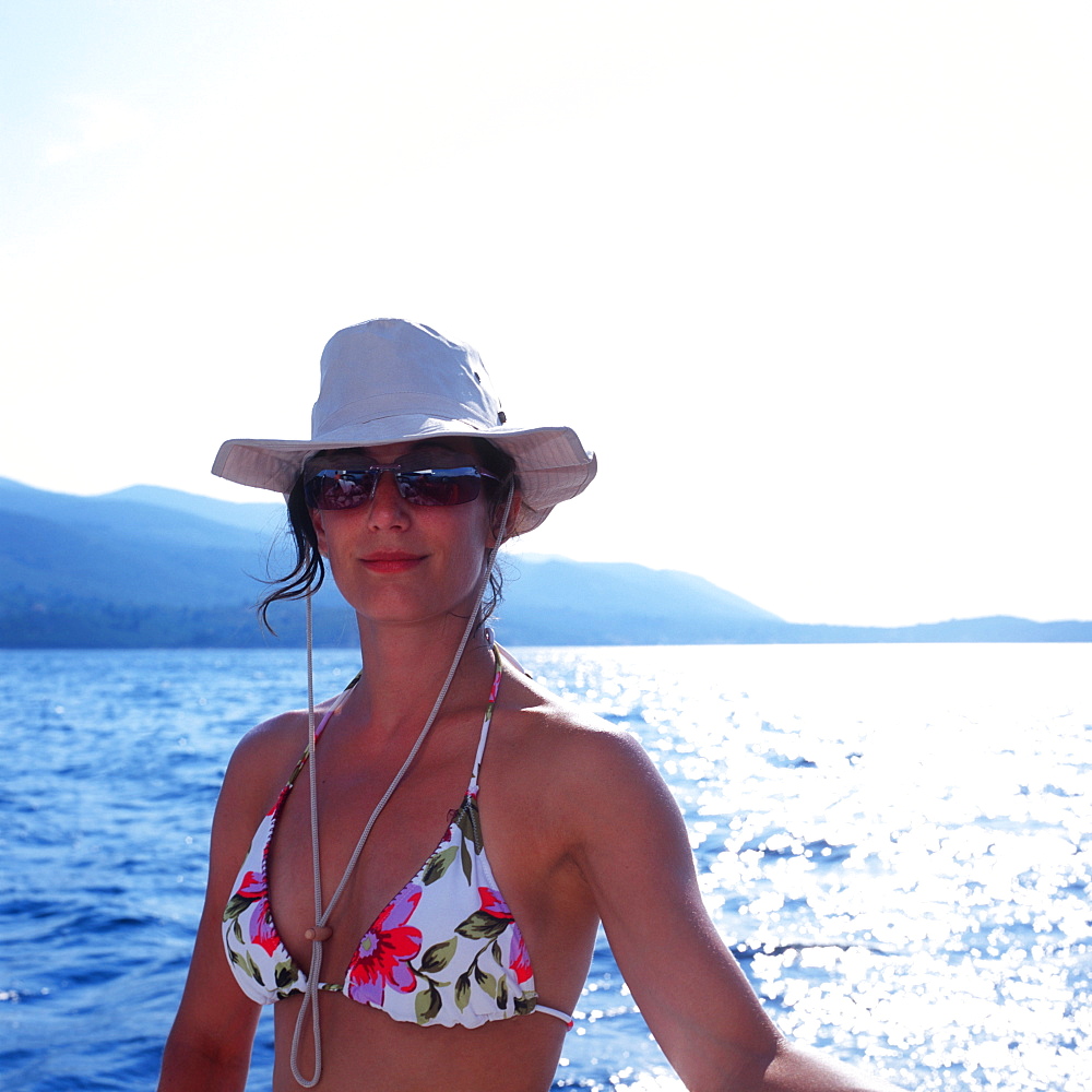 Woman wearing bikini, sunglasses and a hat on a sailboat, Dalmatia, Croatia