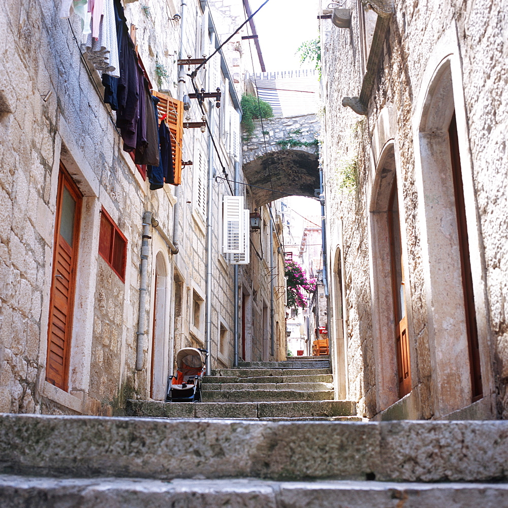 View inside an alley wiht old stone houses and clotheslines at facade, Korcula, Dalmatia, Croatia