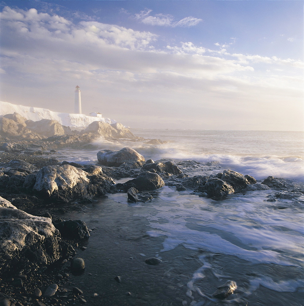 Fog and Rocky Shoreline in Winter with Cap des Rosiers Lighthouse, Northeast GaspâˆšÃ‘ Peninsula, near mouth of St. Lawrence River, Quebec