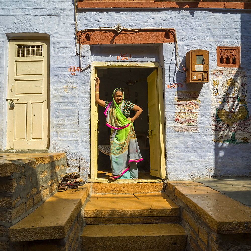 An Indian woman stands in the doorway of her home, Jaisalmer, Rajasthan, India