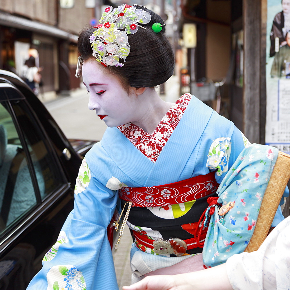 Maiko, apprentice geisha, leaves okiya (geisha house) to get in a car on way to evening appointment, Gion, Kyoto, Japan, Asia