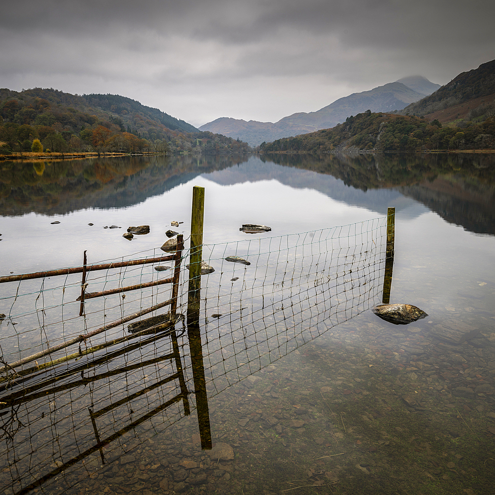 Fence and mountains reflected in Llyn Gwynant, Snowdonia National Park