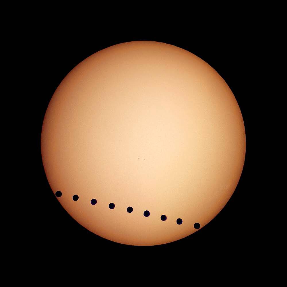 Transit of Venus, June 8, 2004, from Luxor, Egypt. A composite image (layered in Photoshop) of individual multiple shots taken from just after 2nd contact to just before 3rd contact. Taken with a Sony DSC-V1 digital camera shooting afocally through a 40mm eyepiece and on a 90mm apochromatic refractor, equatorially mounted and driven. Shot thru a Baader solar filter, which gives a white Sun. Yellow coloration added in Photoshop.