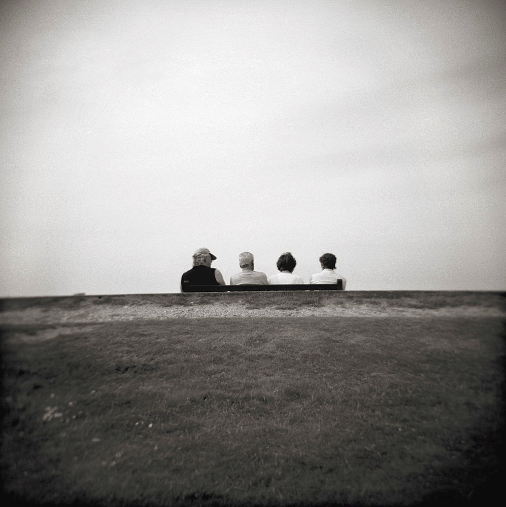 Image taken with a Holga medium format 120 film toy camera of four people on a bench overlooking the sea, Freshwater Bay, Isle of Wight, Hampshire, England, United Kingdom, Europe