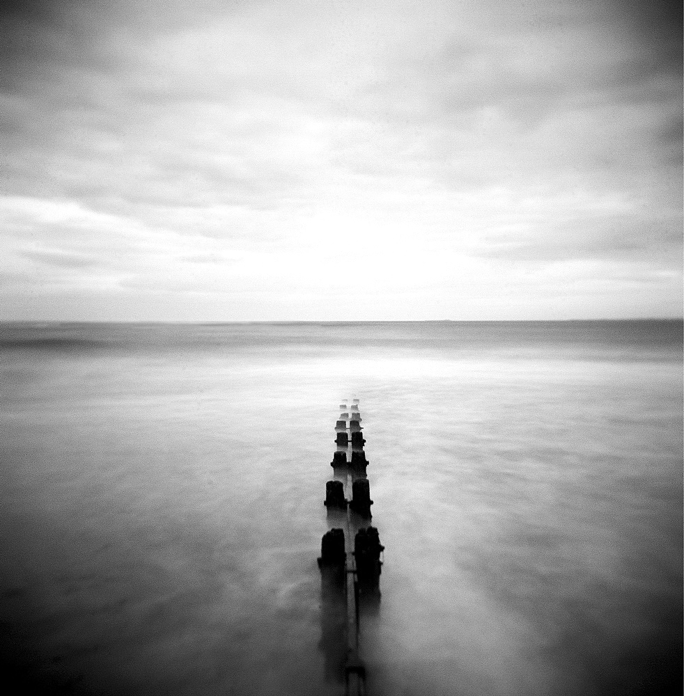 Image taken with a Holga medium format 120 film toy camera of view out to North Sea at dusk with sea washing around old wooden groynes, Alnmouth, Northumberland, England, United Kingdom, Europe