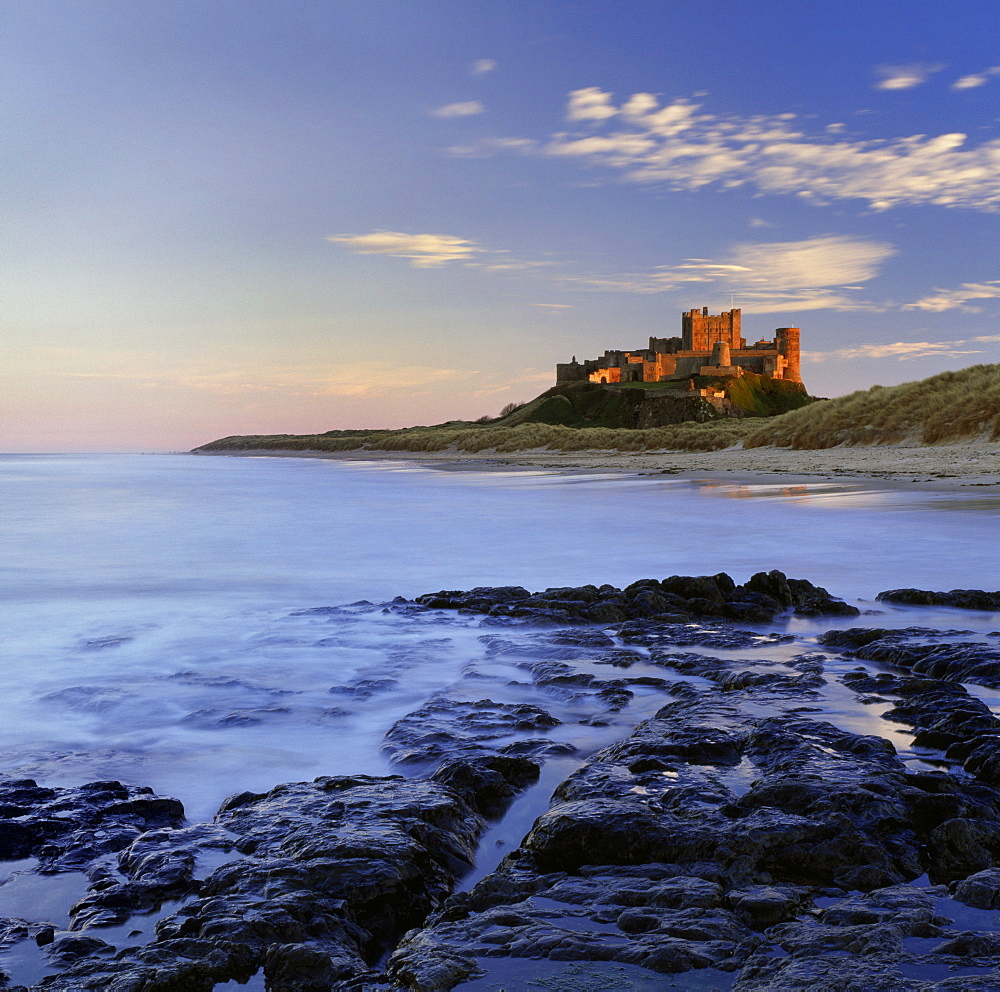 Bamburgh Castle bathed in warm evening light, Bamburgh, Northumberland, England, United Kingdom, Europe