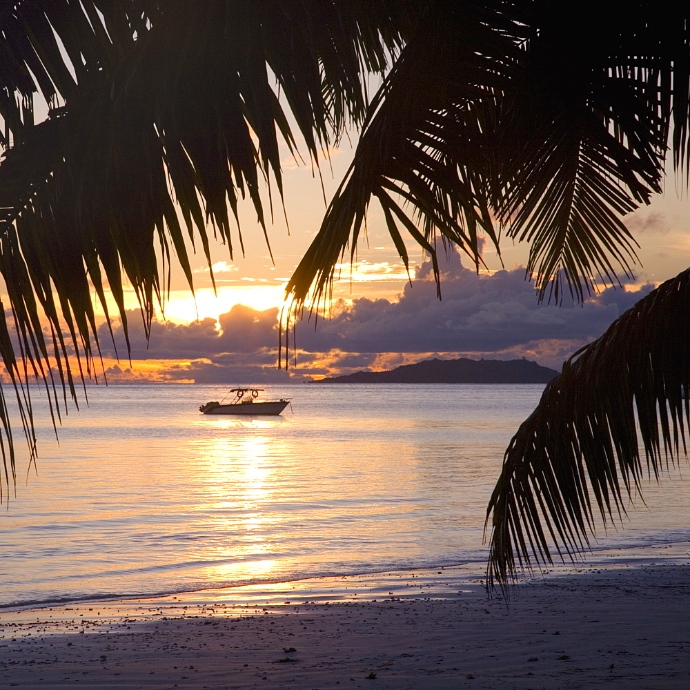 Small boat moored off the beach at Anse Volbert at sunrise, Baie Sainte Anne district, Island of Praslin, Seychelles, Indian Ocean, Africa