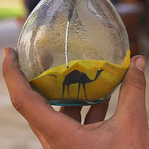 Close up of sand bottle with camel being drawn, on souvenir stall, Jerash, Jordan, Middle East