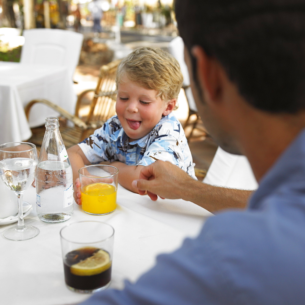 Father and son (6-8) sitting at an outdoor cafe